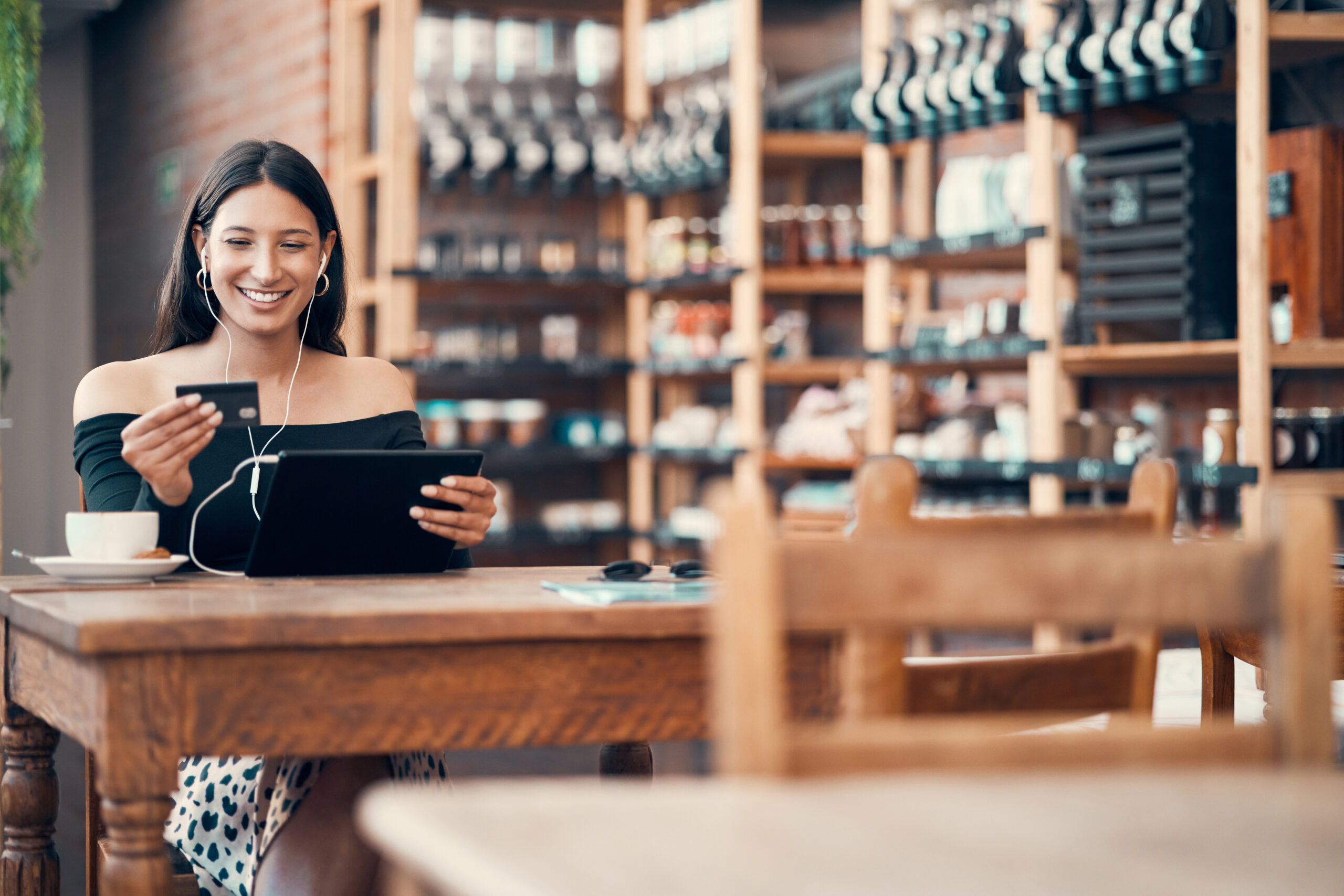 Online shopping, card and cafe while trendy woman holds tablet while wearing earphones and paying f.